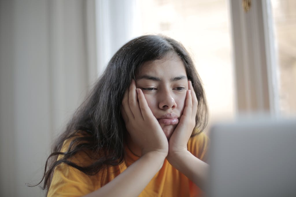 Gelangweilte Frau sitzt vor ihrem Computer und sieht sich unnütze Videos an, um sich die Zeit zu vertreiben.